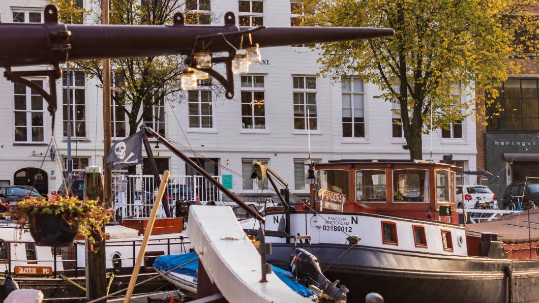 Foto van historische boten in een Rotterdamse haven, met op de achtergrond de Willemsbrug