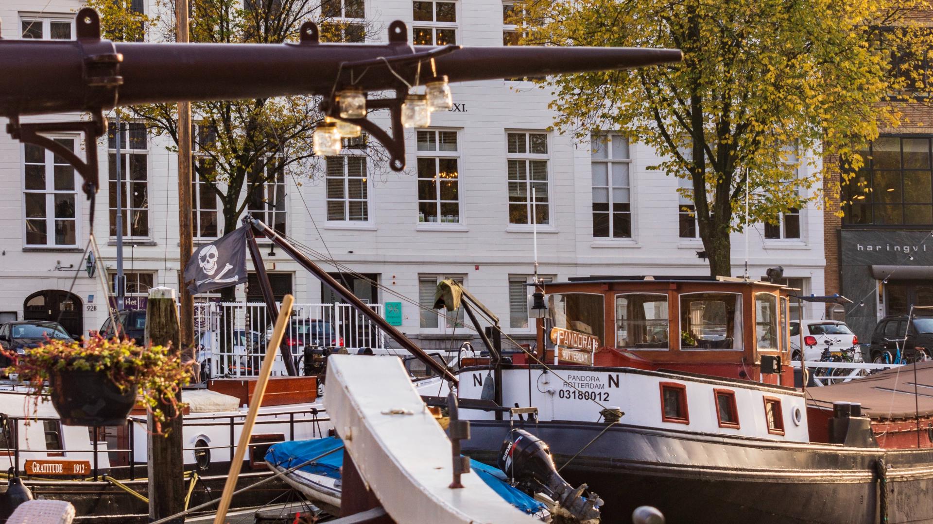 Foto van historische boten in een Rotterdamse haven, met op de achtergrond de Willemsbrug