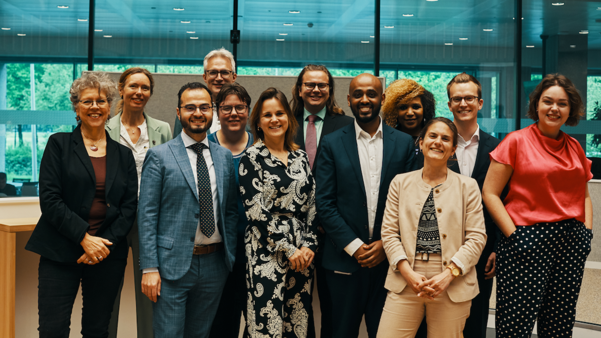 Foto van de fracties PvdA en GroenLinks, met gedeputeerde. De statenleden staan naast elkaar te poseren in de Statenzaal. Ze kijken allemaal lachend in de camera.
