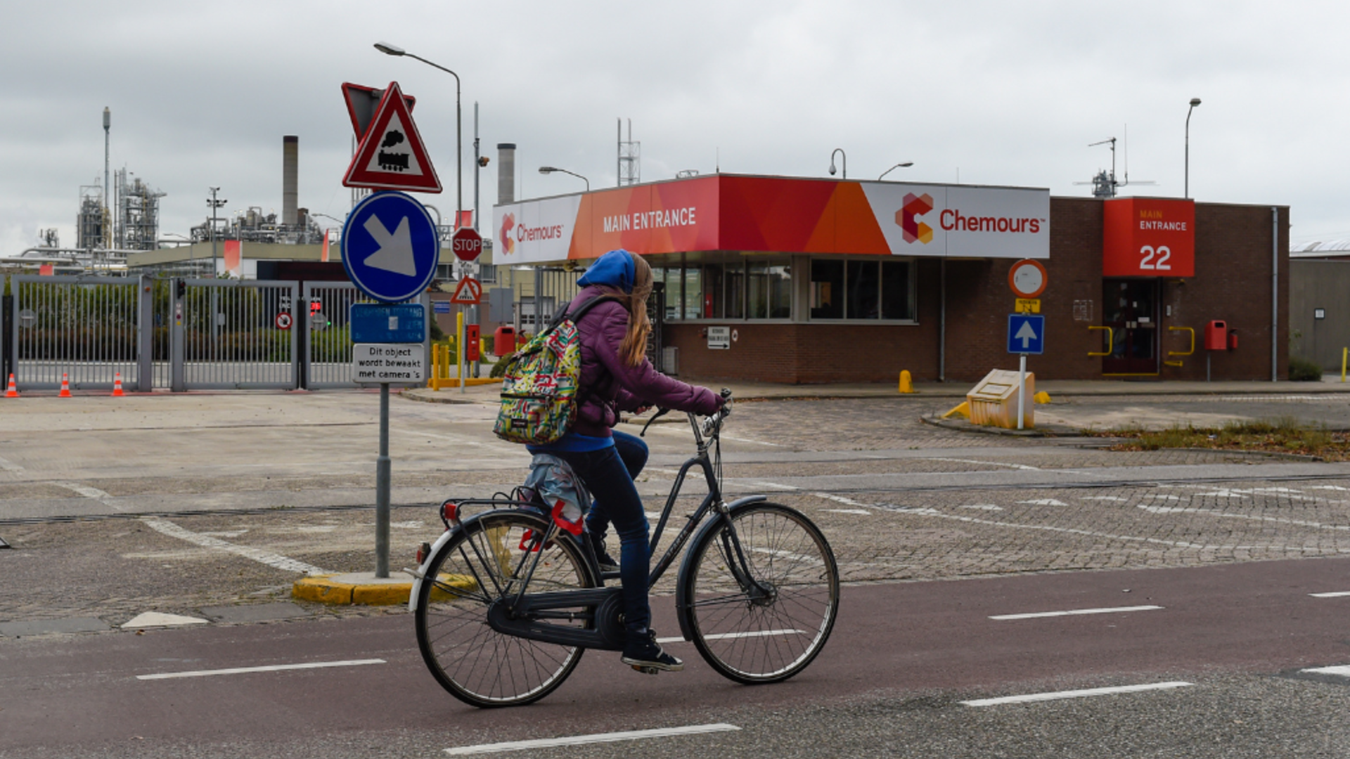 Stockfoto van een jong meisje dat fietst met op de achtergrond een gebouw met het logo van Chemours 